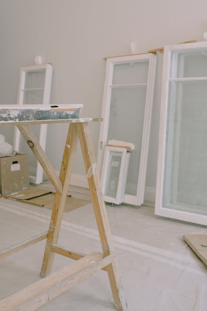 why-choose-us Interior of room with wooden workbench and windows removed from hinges with white frame placed near wall in light room during repair works